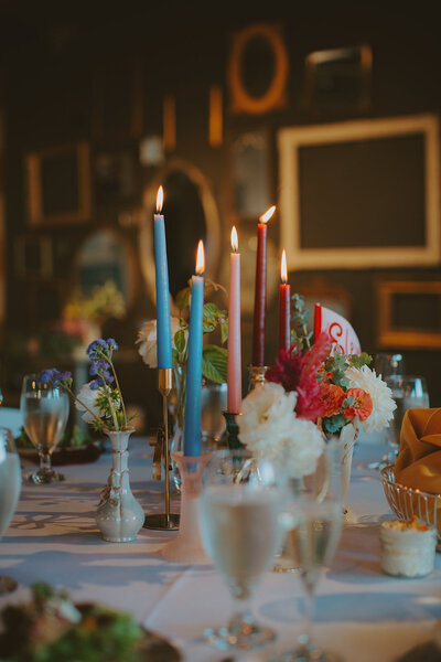 Multi-colored candles and wildflowers in vintage vases at an art gallery wedding