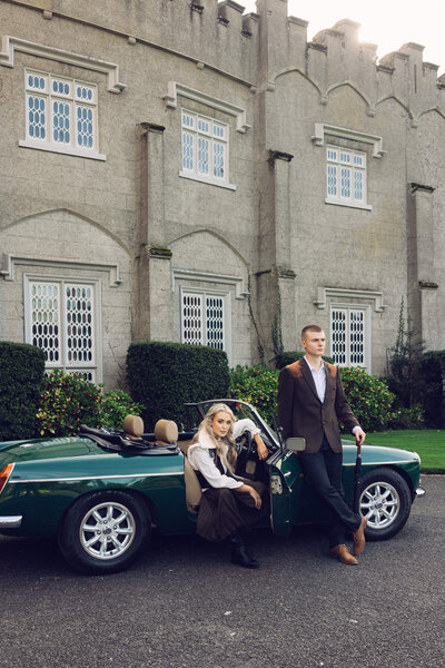 an editorial photo of a couple posing in front of a vintage car at Luttrellstown Castle