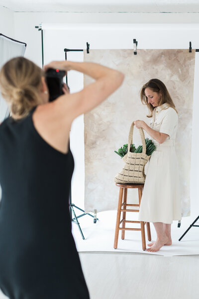 holistic health coach with a canvas bag full of fresh vegetables while brand photographer Lisa Scontras photographs in her studio
