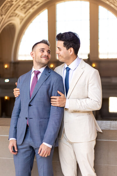 Two grooms look at each other at their gay SF City Hall Wedding