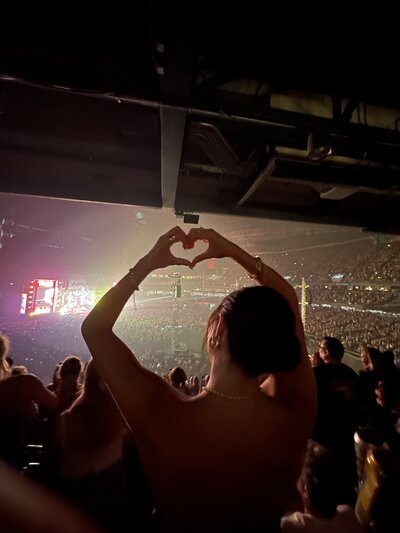 Concertgoer holding heart hands at concert