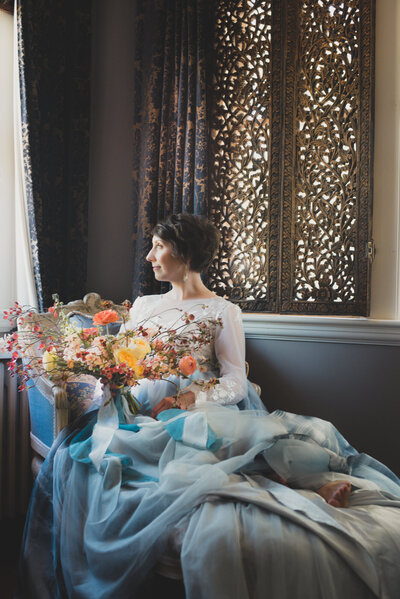 Bride looking out the window while holding her spring bridal bouquet at Villa Marco Polo, Victoria, BC. Photo by Helene Cyr - Fleuris Studio & Blooms