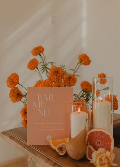 Table of candles and orange flowers placed by Raleigh wedding planners