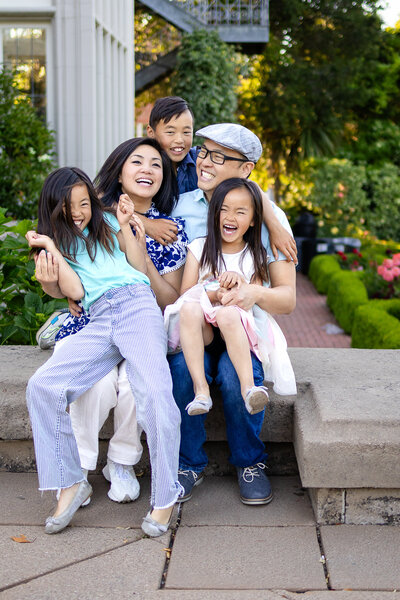 A playful family of five shares laughter and hugs during an outdoor session with Ellobelle Photography.