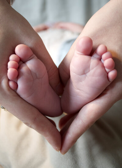 Mum holds babies feet in a heartshape