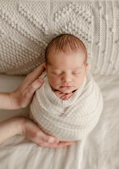 newborn baby girl posed on all white fabric for her denver newborn photos