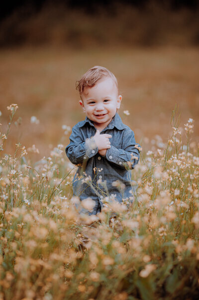 Toddler smiling while standing in a field of wildflowers