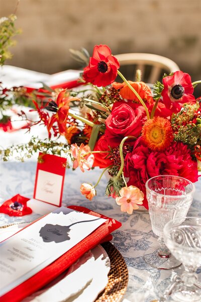 red floral centerpiece on tablescape with layered place setting