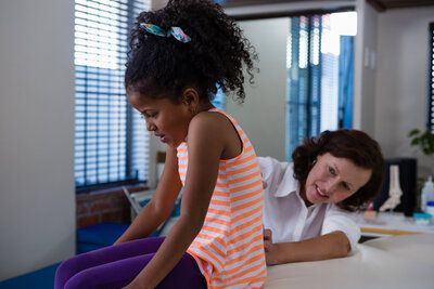 physiotherapist-examining-back-of-girl-patient-in-2023-11-27-05-17-41-utc