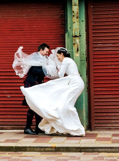 Bride and groom in barrowlands in Glasgow infront of red shutter