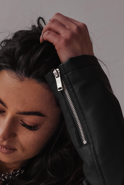 closeup shot of a woman touching her hair wearing black leather jacket