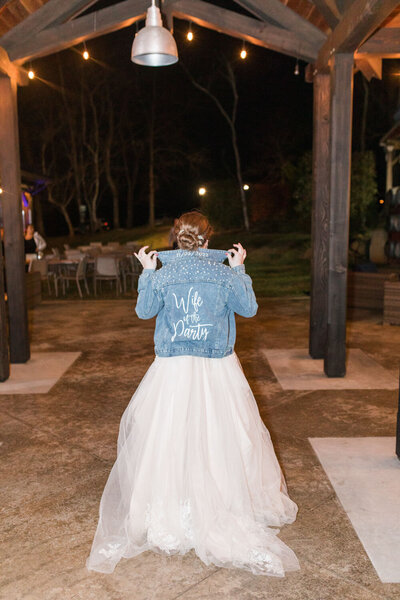 Bride wearing denim jacket with ‘Wife of the Party’ text