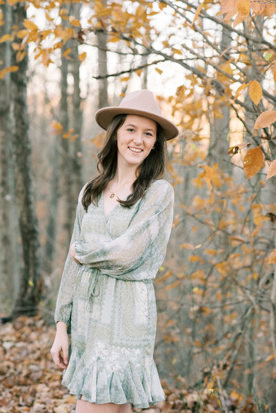 High school senior standing in front of yellow flowers holding her hair