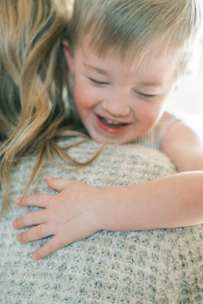 Mom kissing baby feet and toes with eyes closed and smiling with brown curly hair by Portland Family Photographer Emilie Phillipson Photography. 