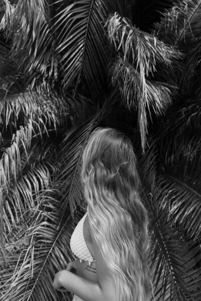 Girl posing with long blonde hair in tropical trees