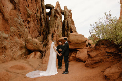 photo of groom holding bride while surrounded by large red rock formations taken by Adventure elopement photographer in breckenridge