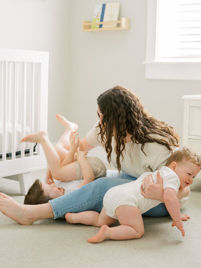 Mother playing with two young children on a carpet