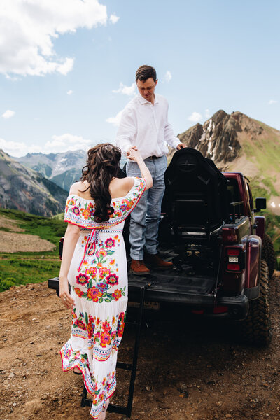 Groom helps bride into jeep in the yankee boy basin in  Ouray, Colorado.