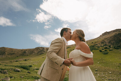 A bride and a groom holding hands running down a mountain in Breckenridge, Colorado. Photo by Jaimee Raneigh Photography. 