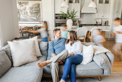 Jessie and Adam smiling at each other while sitting on the couch