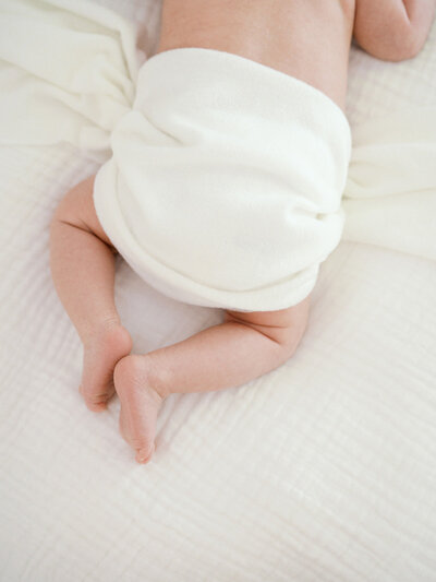 A close-up of the back of a baby wrapped in a white blanket at a newborn photography session in Richmond by Katie Stansfield Photography.