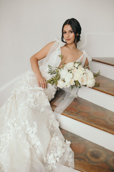 Woman on stairs in her wedding dress holding bouquet
