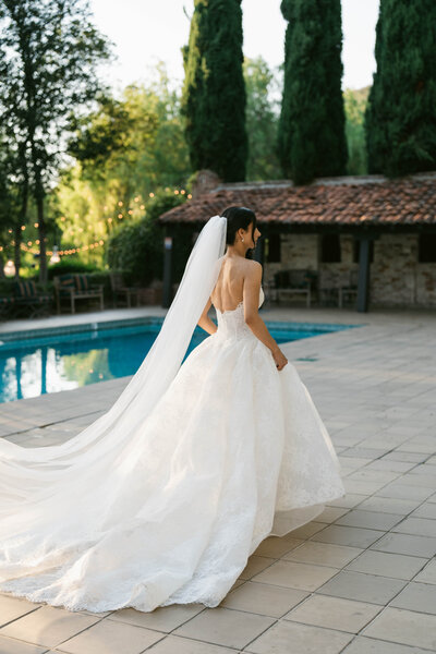 A stunning outdoor wedding ceremony in Scottsdale, Arizona, with a breathtaking mountain backdrop. Guests in vibrant pink dresses watch as the bride and groom exchange vows under a floral arch at sunset.