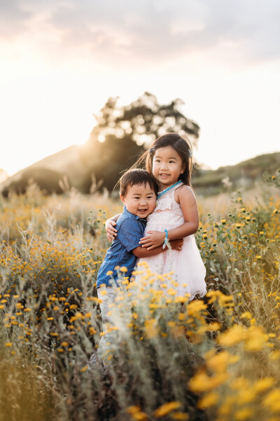 toddler holding wildflowers smiling in the field