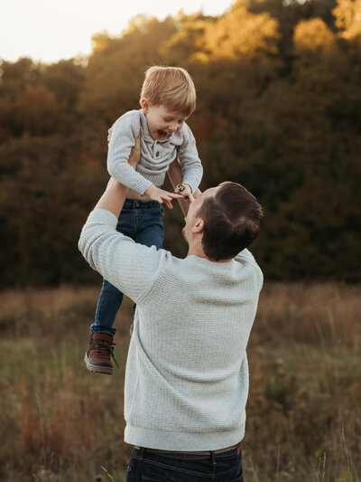dad holding son up in air for fall family portraits