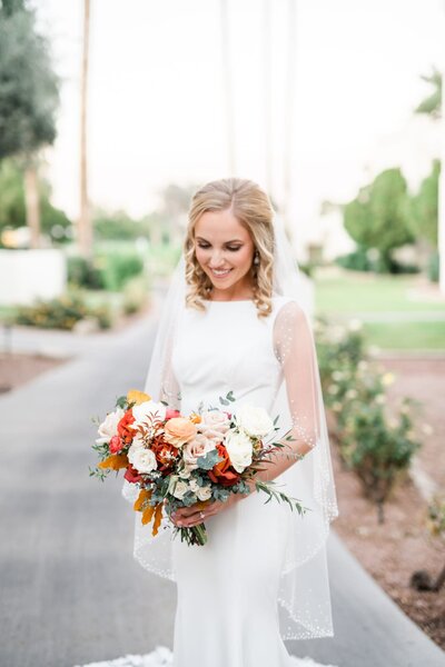 Bride holding bouquet and looking down at flowers smiling