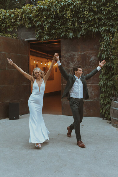 Wedding couple joyfully dancing their way out to their reception in the Pacific Northwest, photographed by Bare Bones Photo