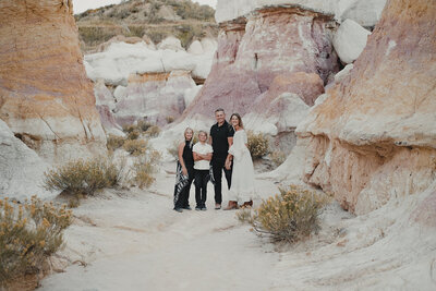 A family of four poses together, while dressed formally at the Colorado paint mines which is an ethereal white and pink sandstone Park located in Calhan, Colorado.