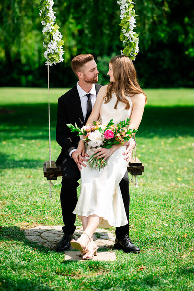 A newlywed couple at their Richmond wedding sit on a swing admiring one anther, taken by Nathan Sottung Photography
