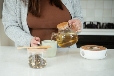 Chantal Hewitt at the kitchen island pouring herbal tea in a brown shirt and grey cardigan - Family Autism Support Coach at Chantal Hewitt Coaching12