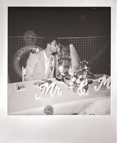 black and white poloroid of bride an groom kissing at their reception