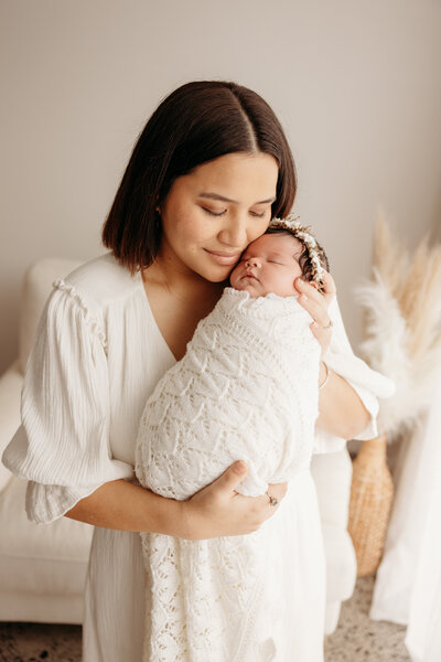 A mother holding  her newborn baby for a newborn photoshoot in the auckland studio of michelle kelly photography
