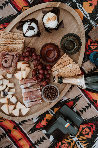 Rustic charcuterie board with meats, cheeses, cupcakes, and champagne at Breckenridge elopement picnic.