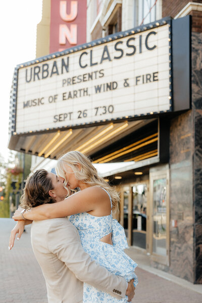A man kissing his girlfriend in front of tall grass.