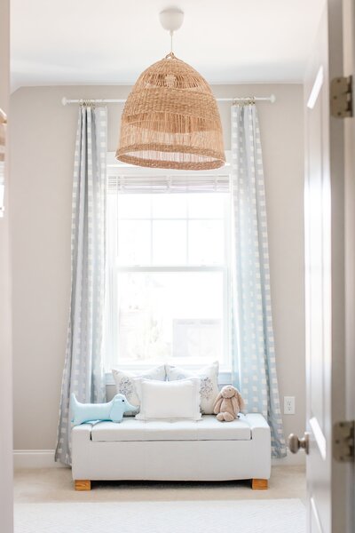 Cozy, styled room with a window, chair, and woven light fixture.