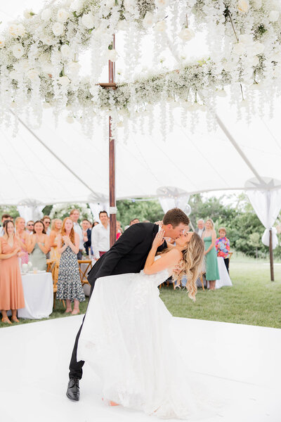 Bride and Groom kissing under flowers at their reception