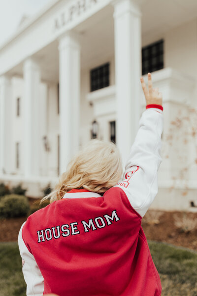 Sophie wearing a pink jacket that says house mom on the back