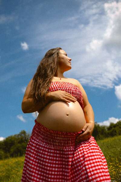 Expecting mother in black underwear and a mesh dress holding her belly in downtown Ames.