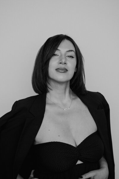 A modern edgy, fine art image of a woman, staring directly at the camera, while wearing black with a beautiful Gold Mountain necklace and dark red lips.