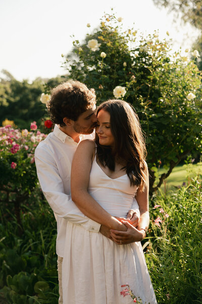 couple holding each other next to tree