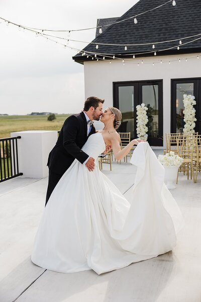 photo of bride in sweetheart neckline wedding dressand groom in black tuxedo going for dip kiss photo by mary wiebe photography