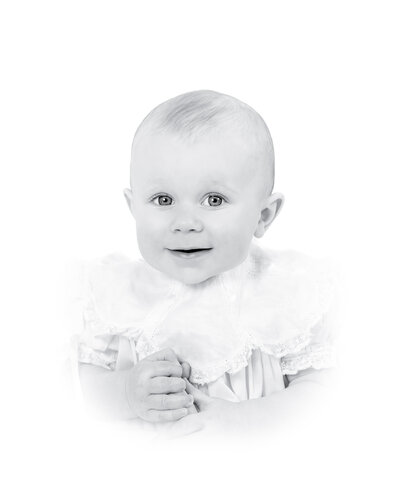 Classic heirloom portrait of a young child with a soft smile, dressed in a traditional outfit with delicate pleats. This timeless and artistic children’s portrait reflects the refined and elegant style of a Birmingham portrait photographe