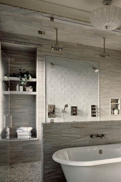 Boston brownstone designers renovated a primary bathroom with light grey Waterworks tile and a freestanding tub, showcasing refined craftsmanship by top interior designer companies in Boston.