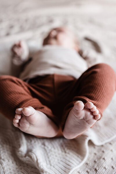 Foto van liggende baby met blote voetjes waarbij de voetjes in de voorgrond scherp zijn en de rest van de baby onscherp is