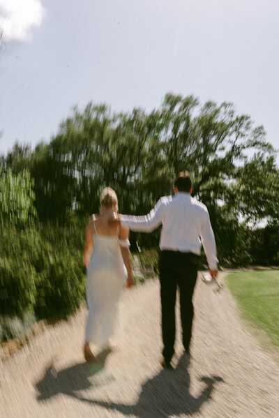 A motion blur photo of a wedding couple walking along a gravel road lined with Louisiana oak trees. 
