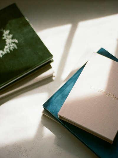 three heirloom photo albums in luxe velvet or linen with sheer silk ribbon draped across from fauna & film